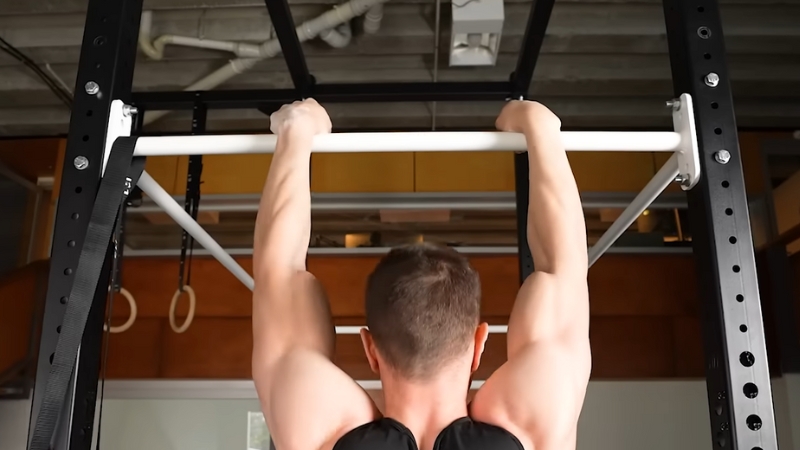 A Man Gripping a Pull-Up Bar During a Workout, Focusing on Building Grip Strength and Upper Body Endurance