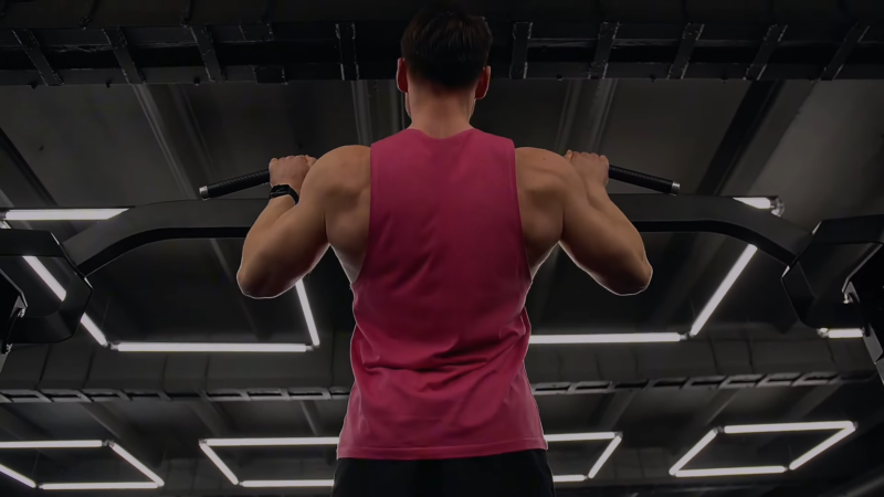 A Man in A Gym Performing Pull-Ups on A Bar