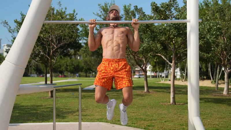 A Man Performing Pull-Ups at An Outdoor Gym, Highlighting the Activation of His Core Muscles for Stability and Strength